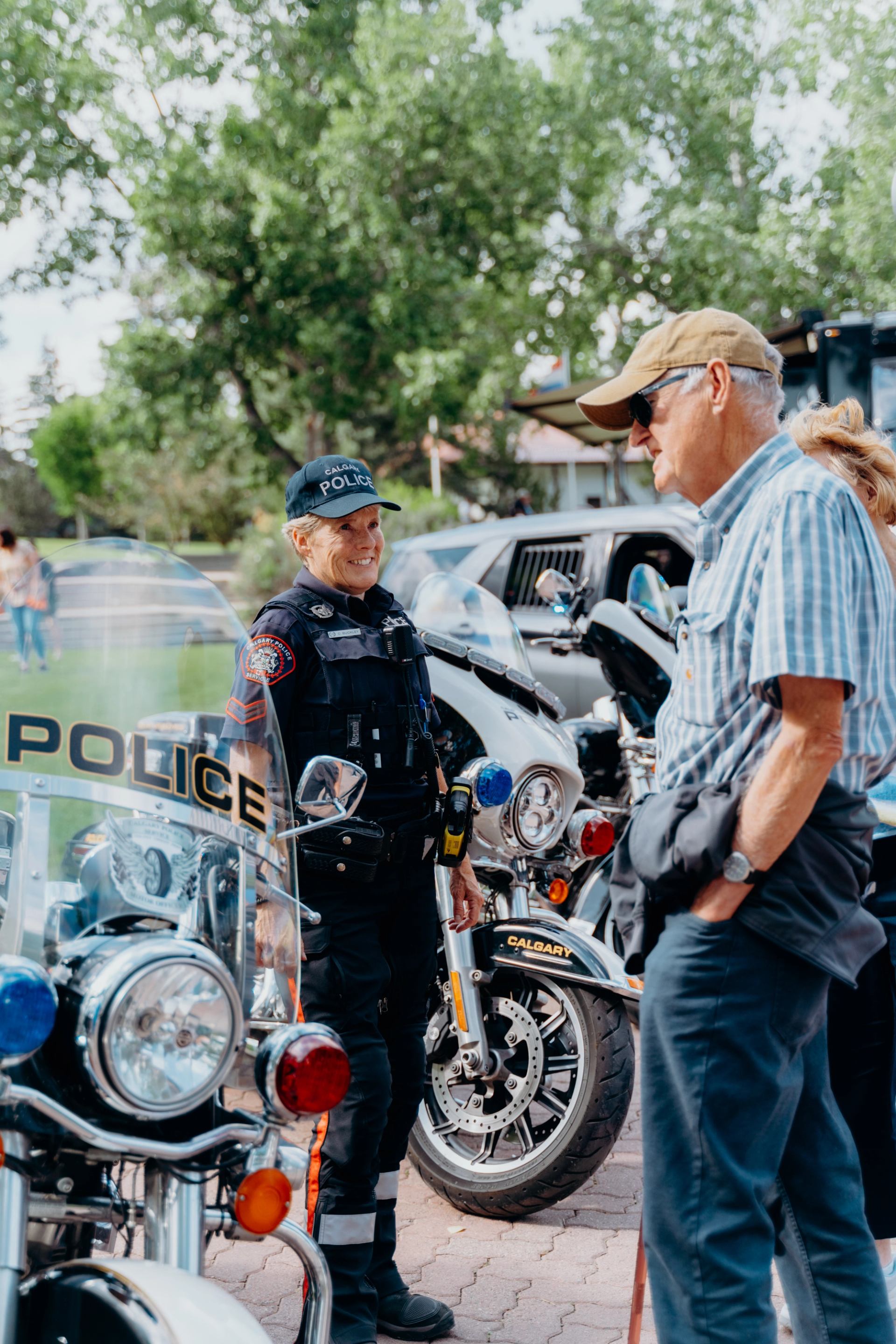 A police officer speaks with guests beside parked police motorcycles.