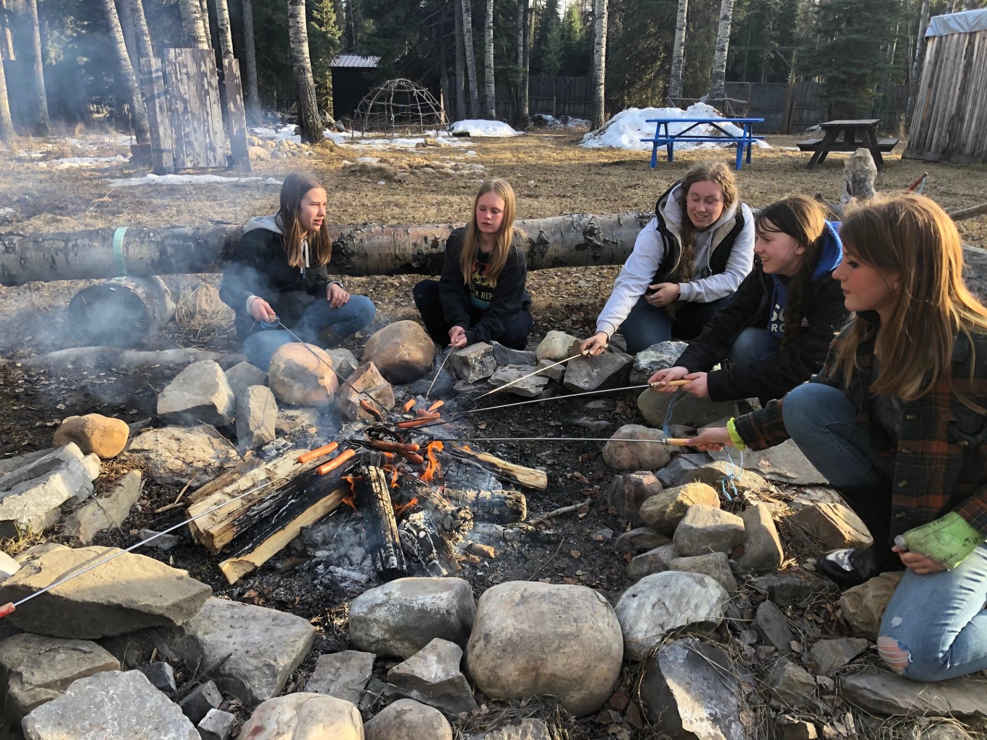 A group of girls around the fire pit