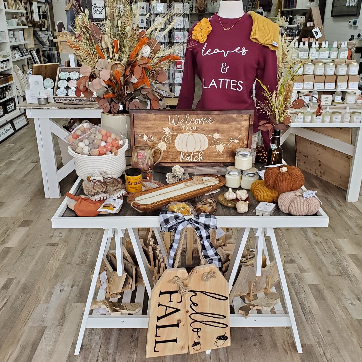 Fall display with pumpkins, candles, and “Leaves & Lattes” sweatshirt at Creative Goods & Co.