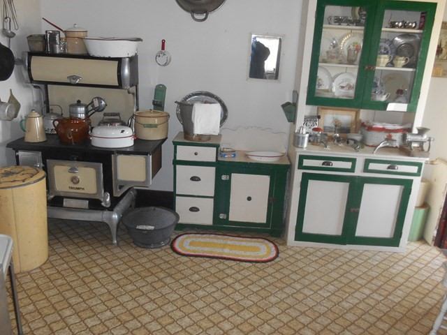 Vintage kitchen with antique stove, cabinets, and retro cookware.