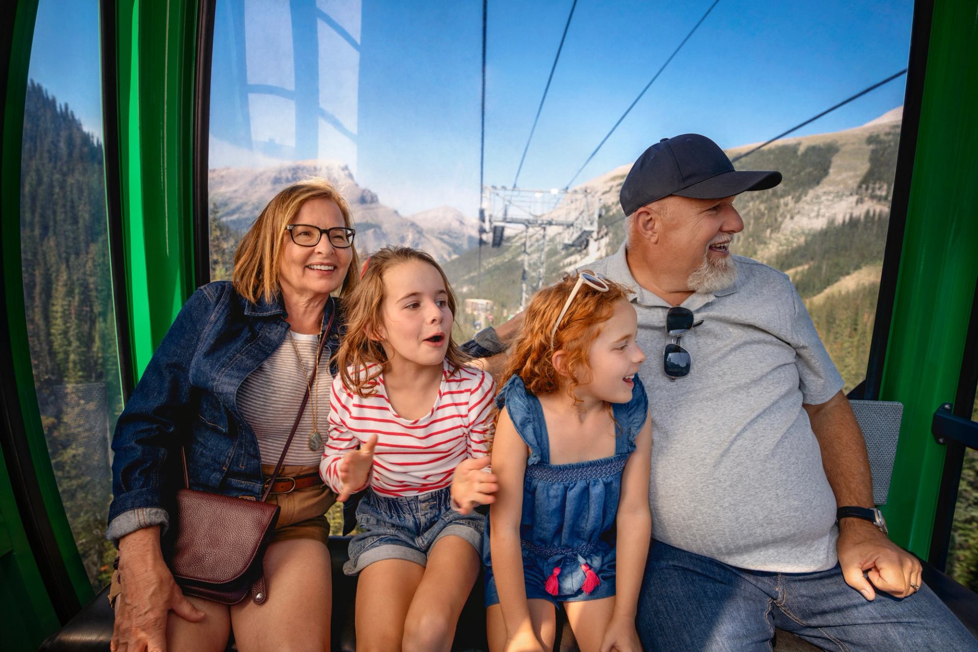 People sit inside a gondola cabin with mountain and forest views outside the window.