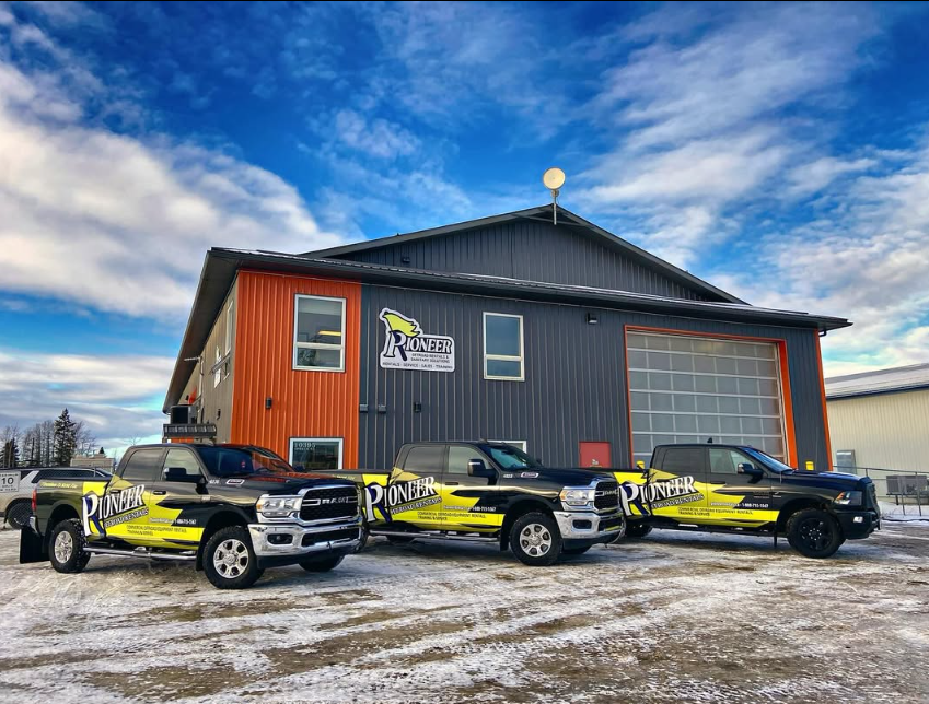 Three branded Pioneer trucks parked outside the rental shop on a snowy lot