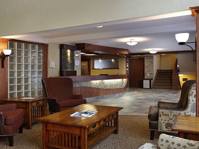 Warm hotel lobby with stone reception desk, cozy seating, and rustic decor.