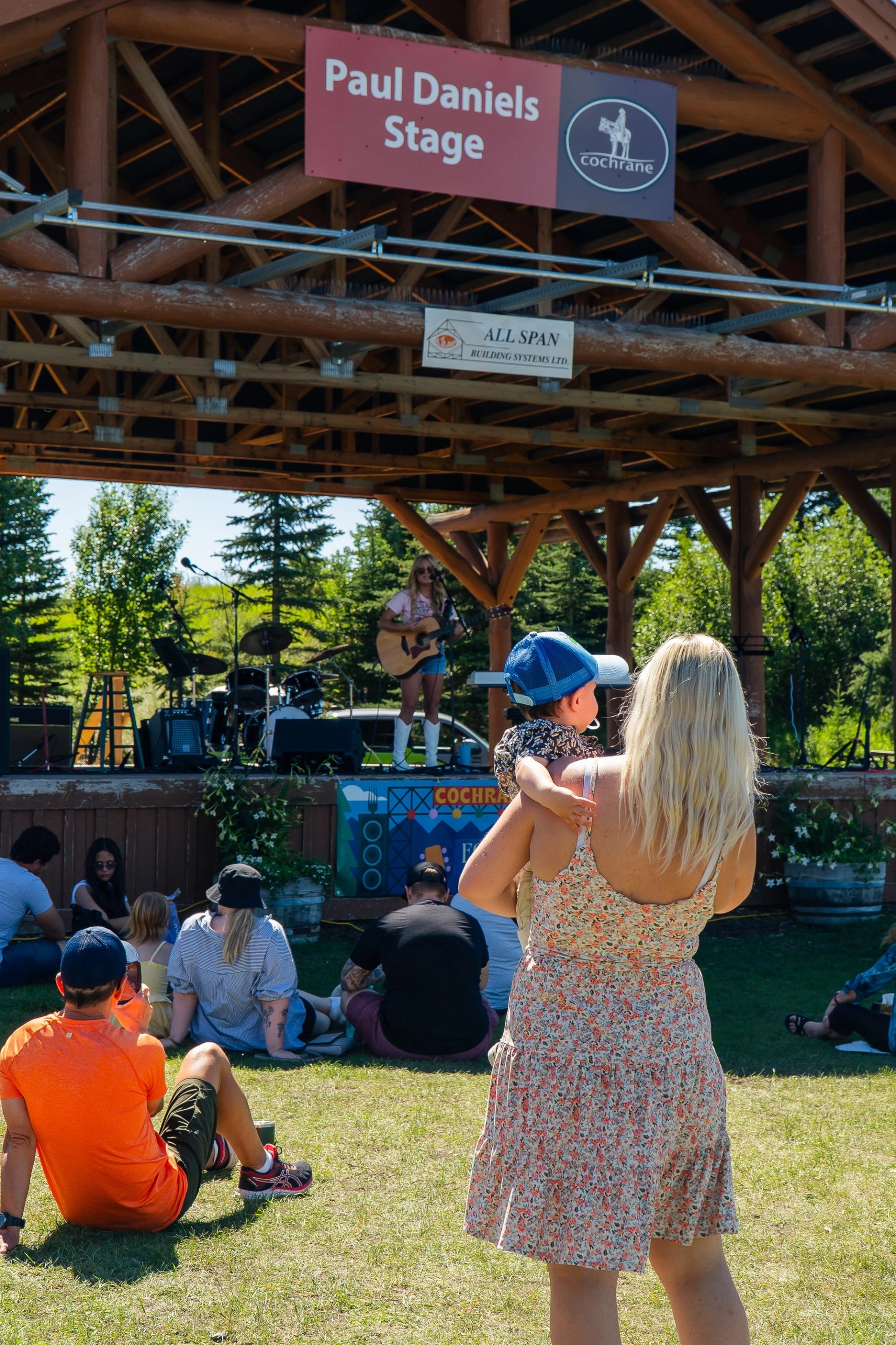 A lady holding a child watching the band play on stage.