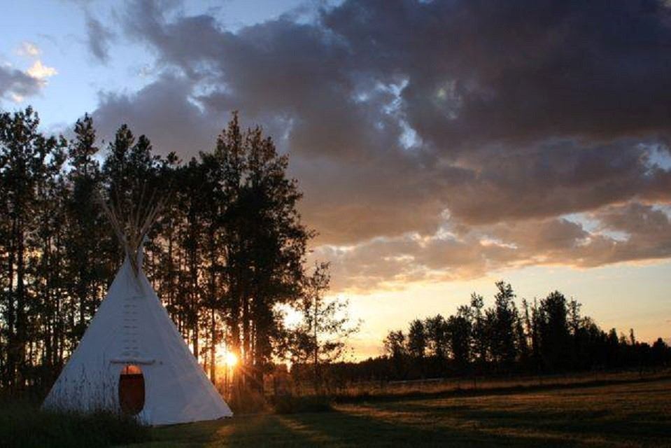A tipi with the sun setting in the background