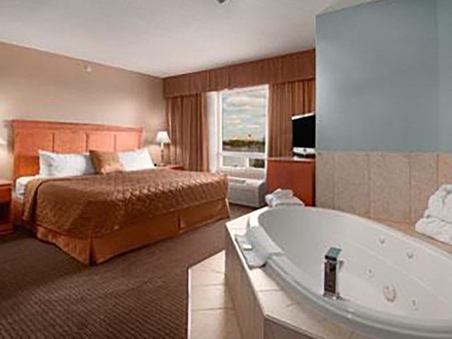King bed and corner jacuzzi tub in a bright hotel suite.