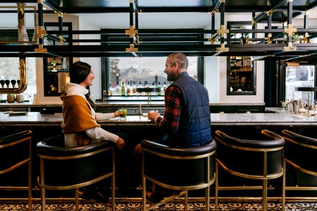 A couple sitting at the bar enjoying cocktails in the Vermillion Room at the Fairmont Banff Springs.