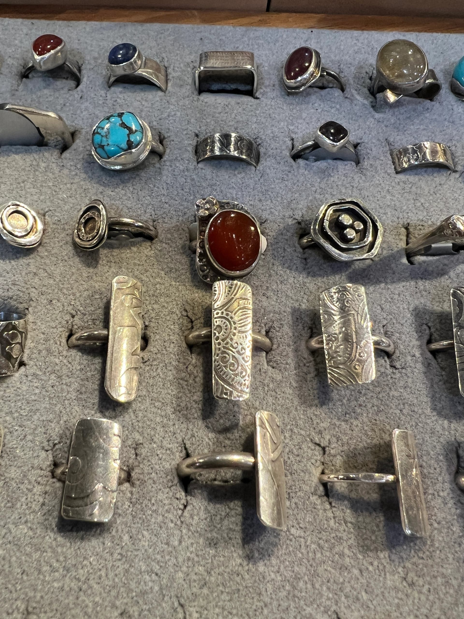 Assortment of handcrafted silver rings set in a display tray.