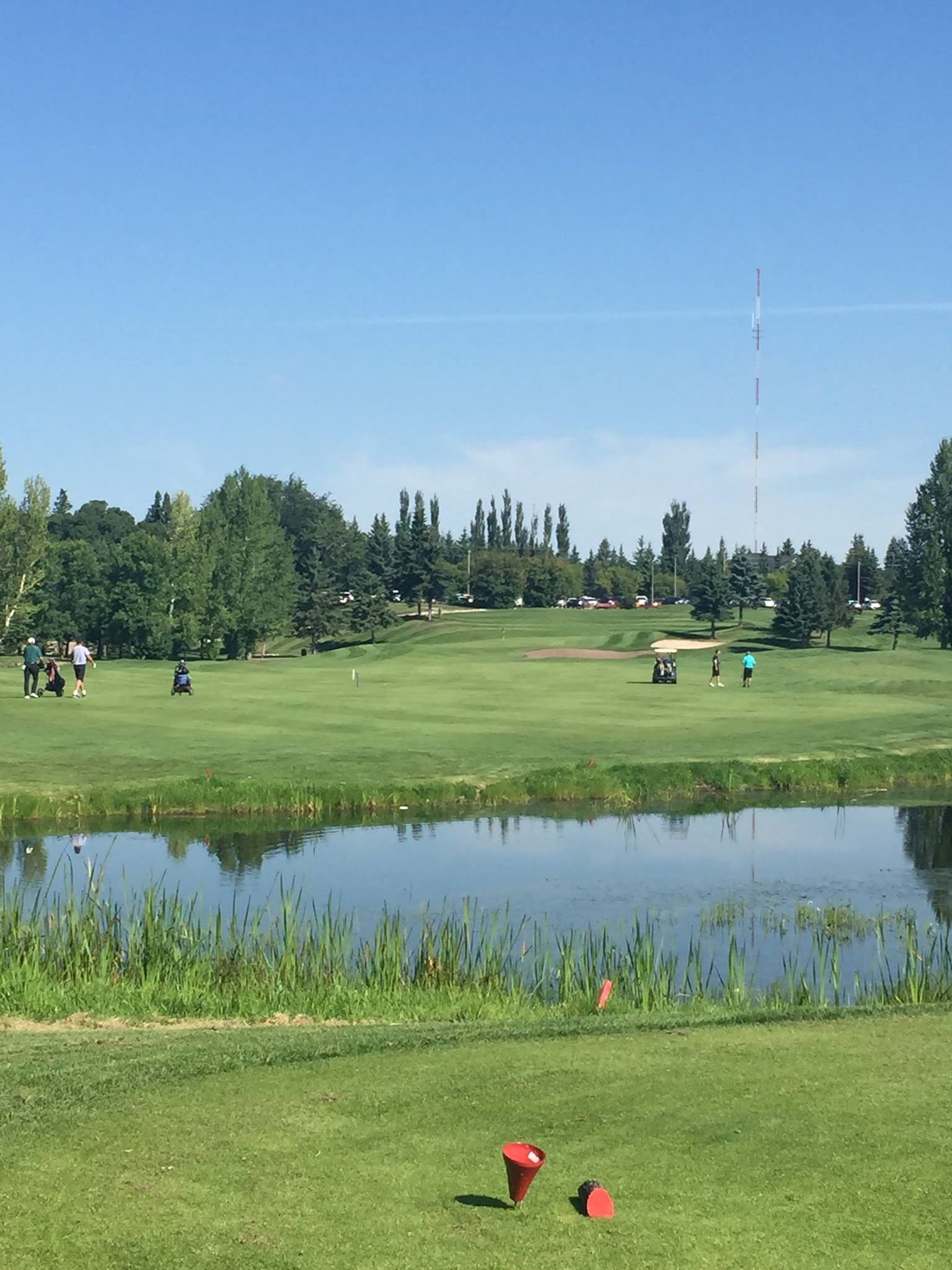 Golf course fairway with a pond in foreground and trees in background