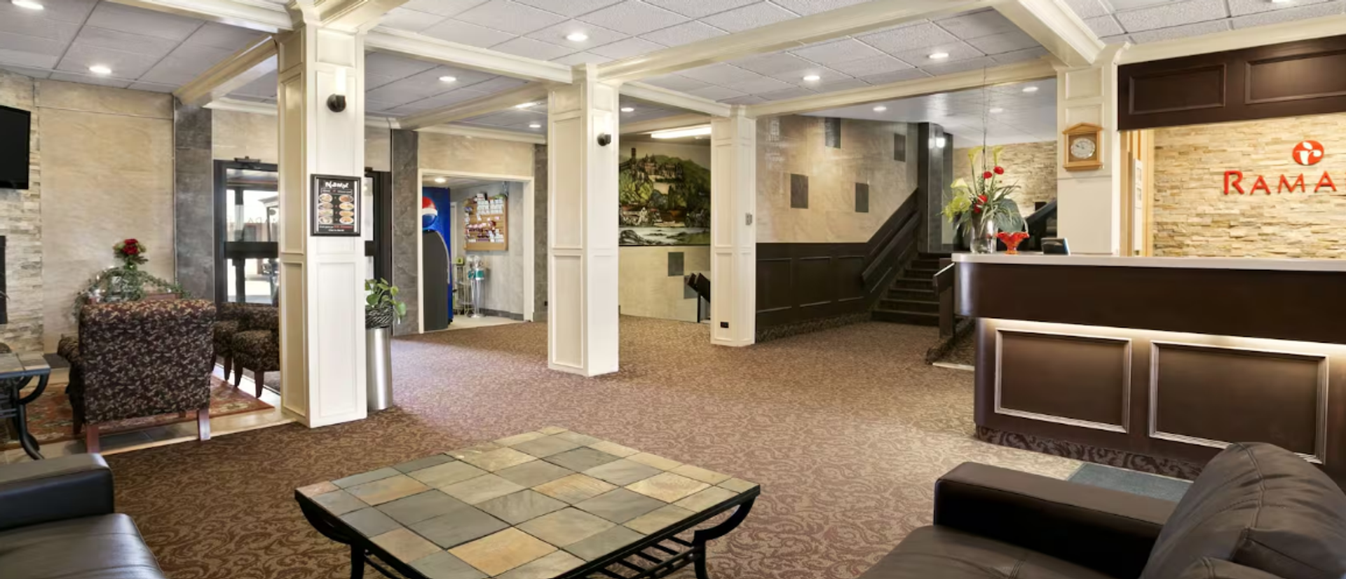 Hotel lobby with front desk, seating, columns, and soft lighting.