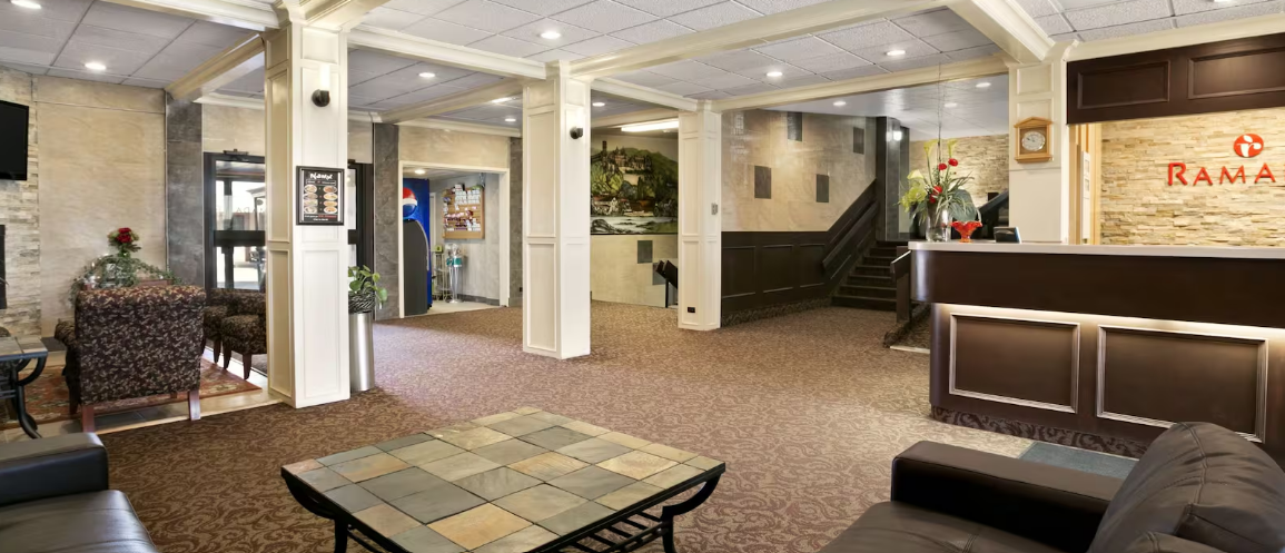 Hotel lobby with front desk, seating, columns, and soft lighting.