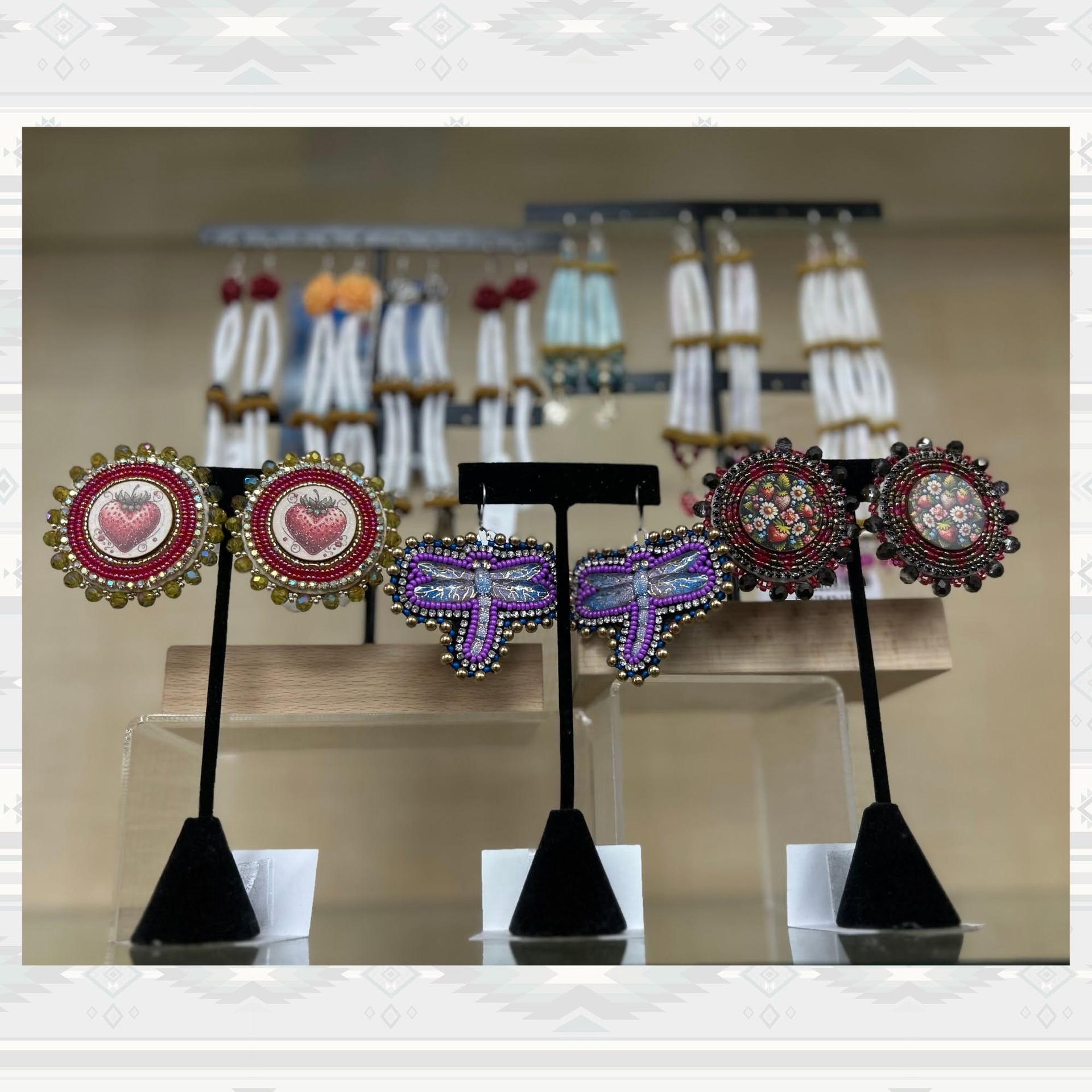Beaded earrings with heart, dragonfly and floral designs displayed on black stands.