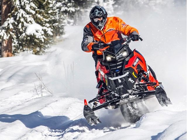A person on a skidoo going through a snowy trail