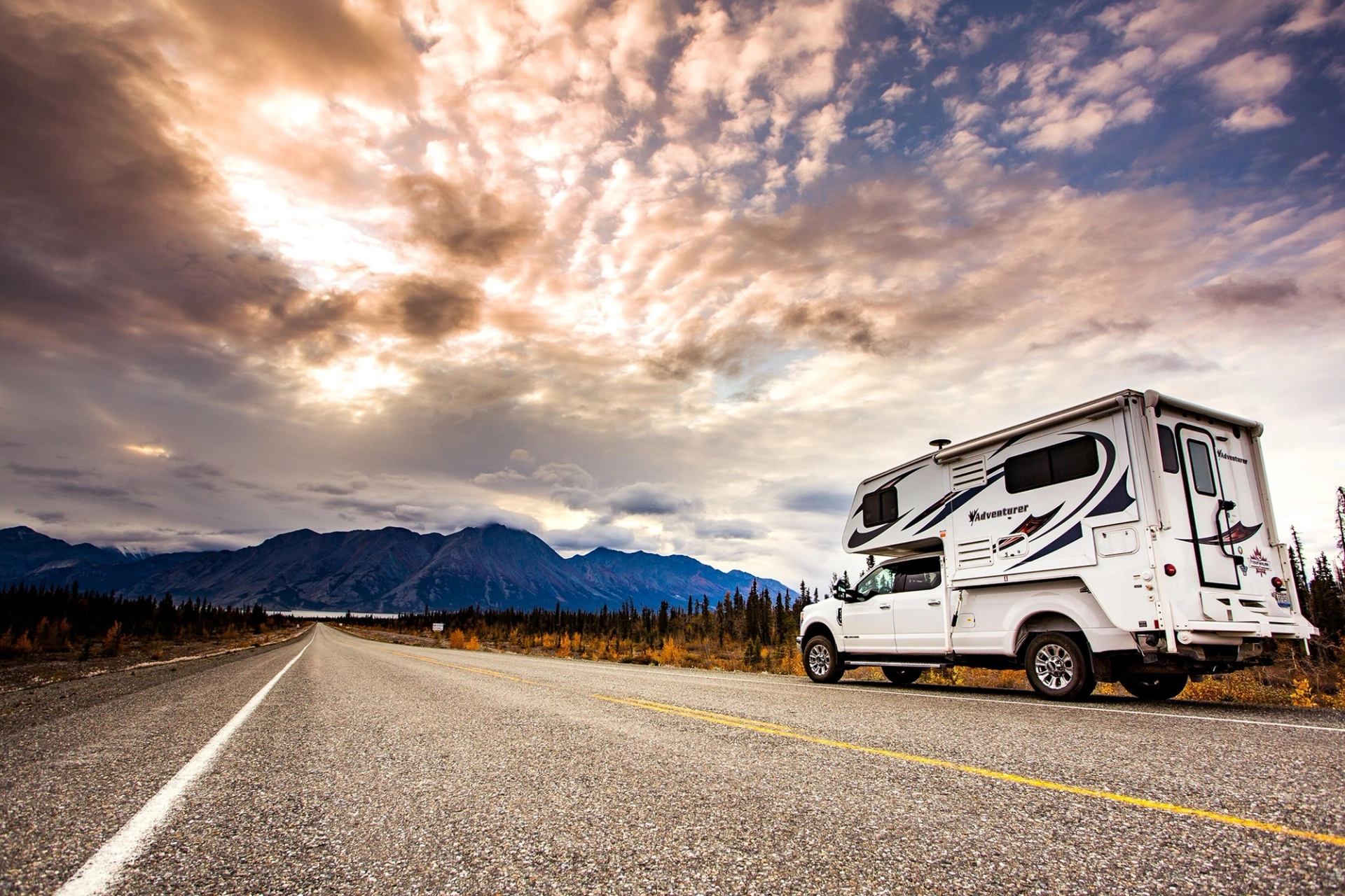 A truck camper driving along the rode