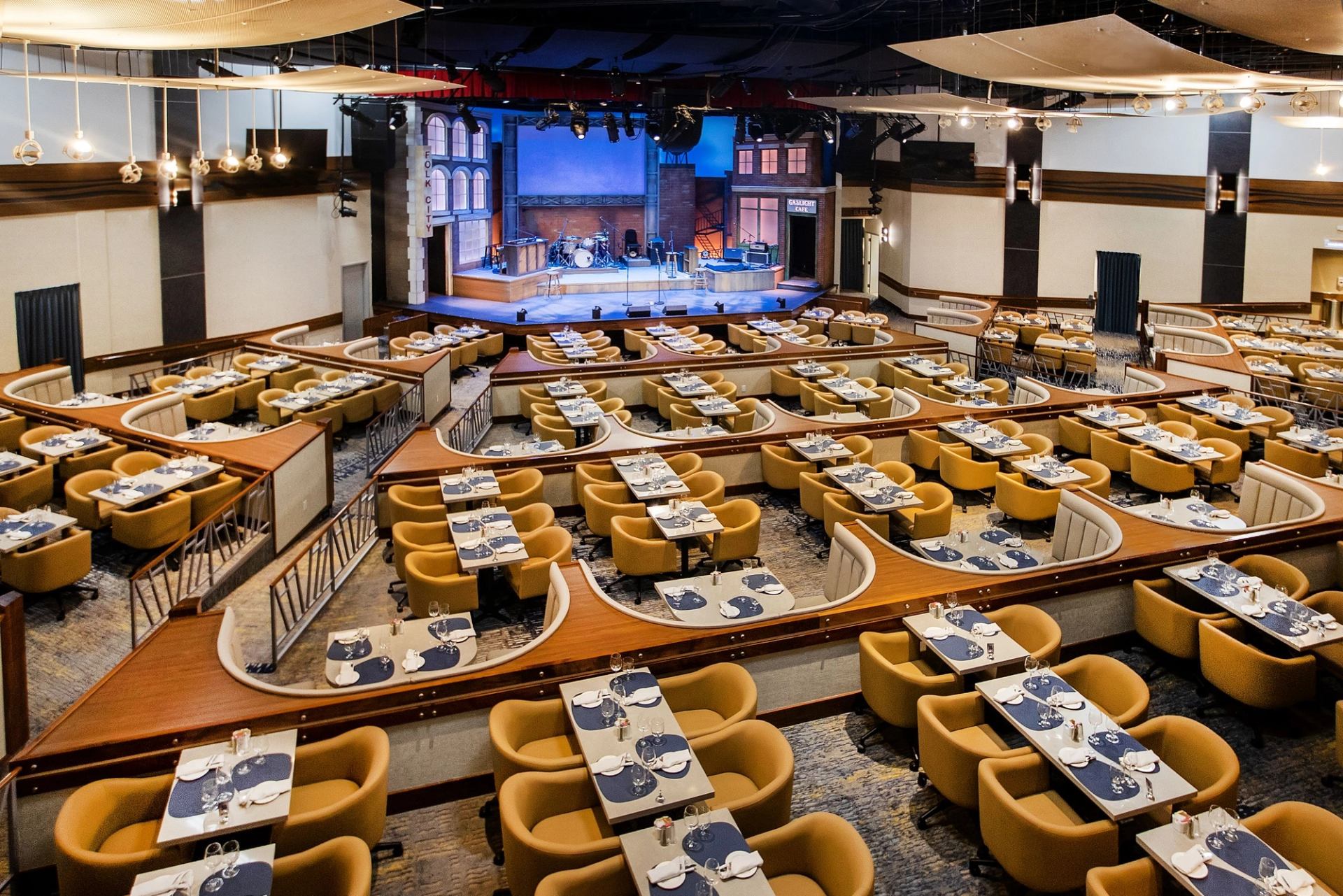 Dinner theatre with curved seating sections facing a stage set with instruments and lights.
