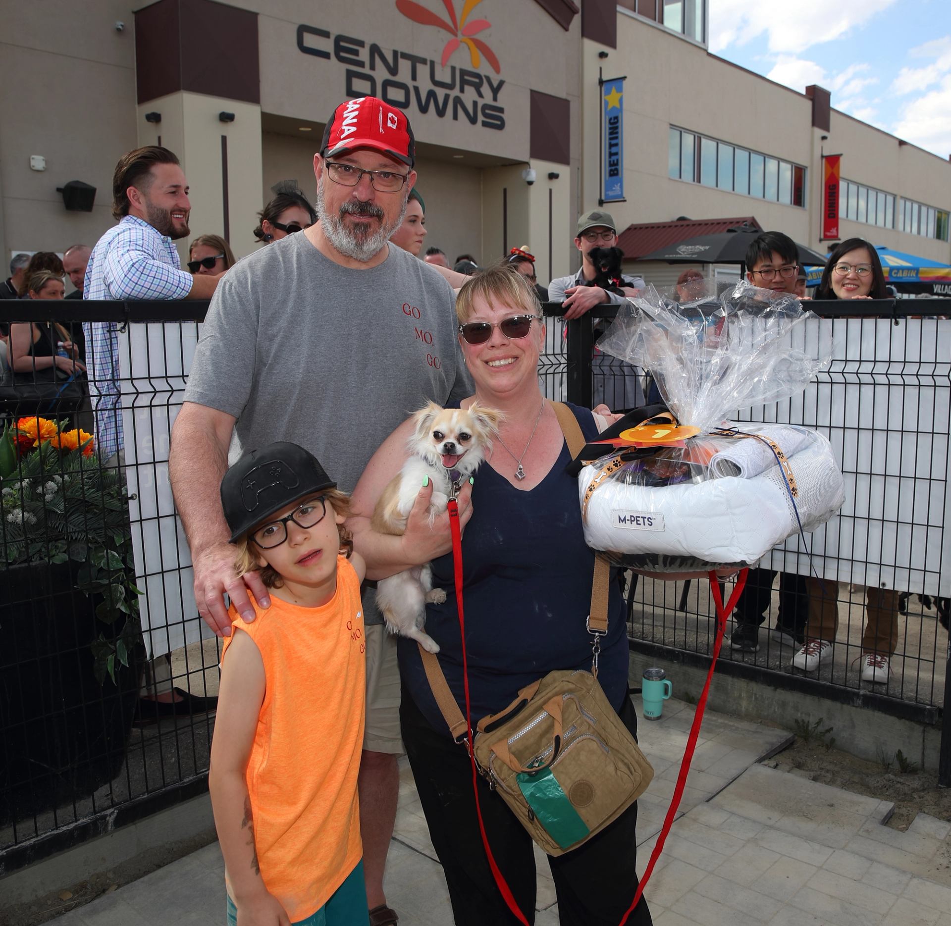 Family holding Chihuahua and gift basket at Century Downs event