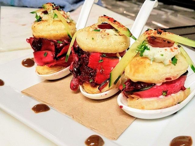 Three colorful gourmet bites with vegetables and herbs served on white spoons.