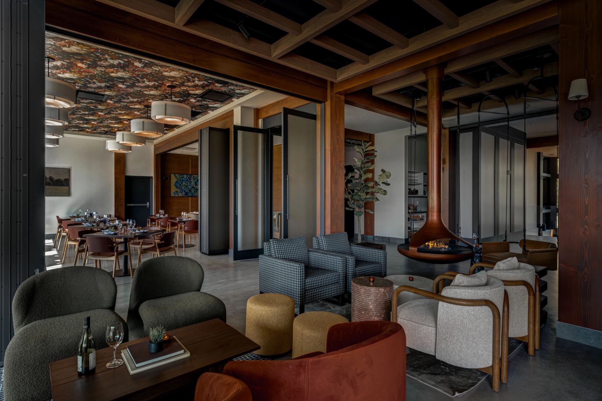 Foxtrot at Spruce Meadows interior with lounge seating, wood beams, fireplace, and dining area beyond.