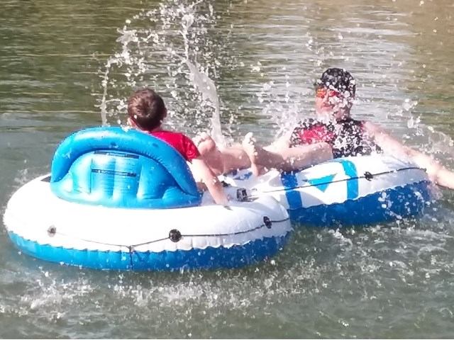 Two people tubing on the river with splashing water.