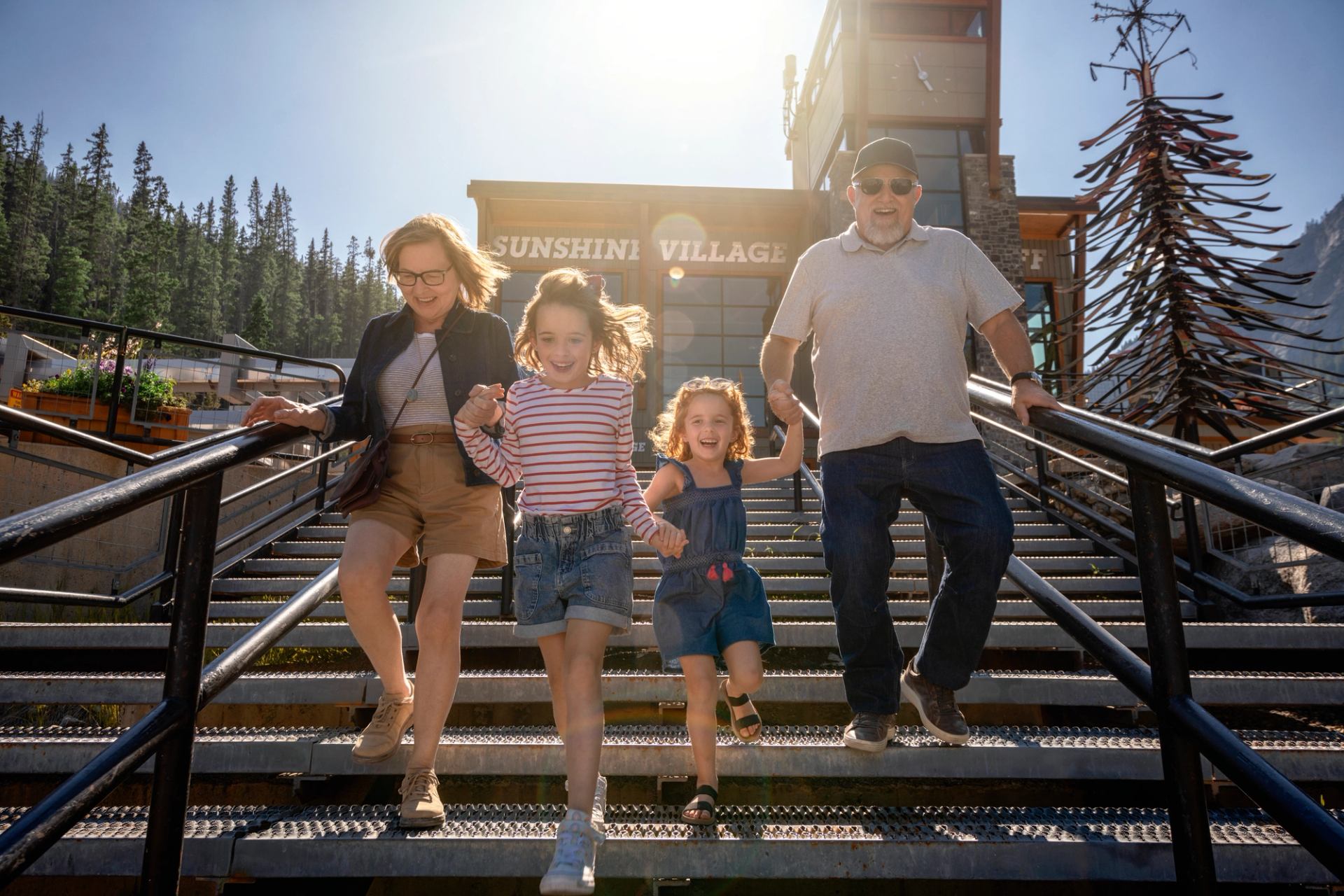 Group of four people holding hands while descending metal stairs at Sunshine Village.