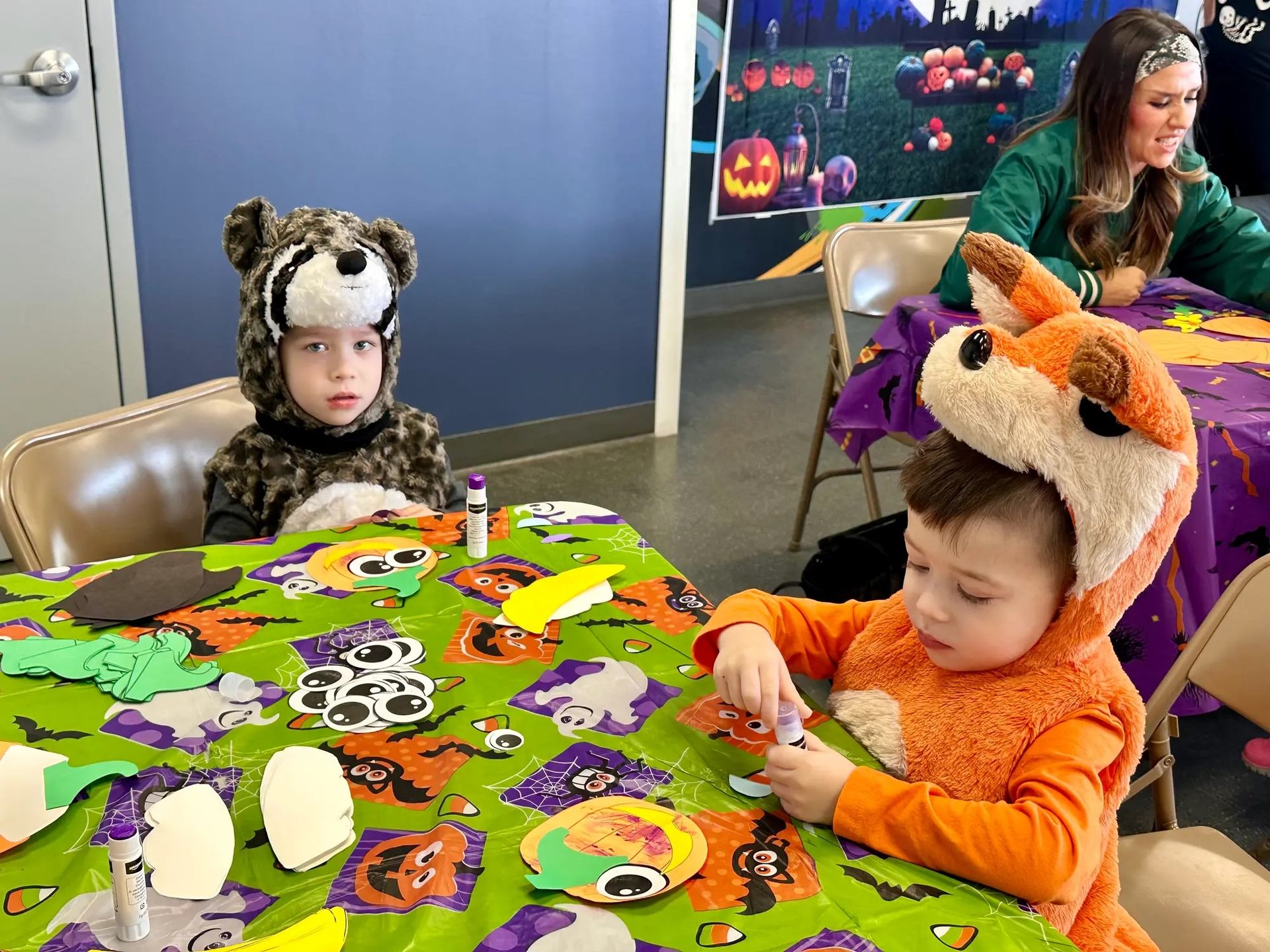 Kids in animal costumes doing crafts at Regional Field House Halloween event.