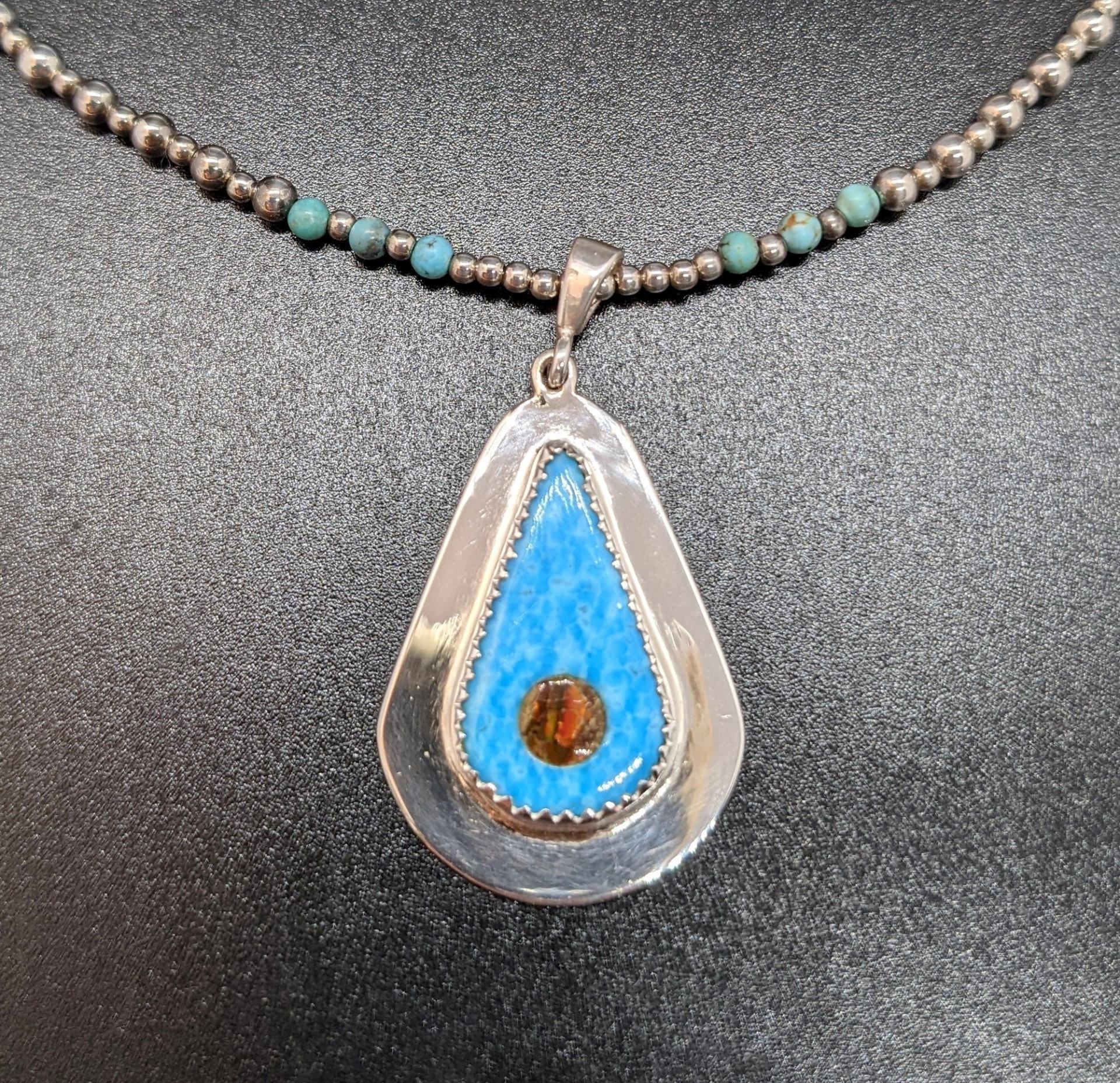 Beaded necklace with teardrop pendant featuring blue and amber stones.