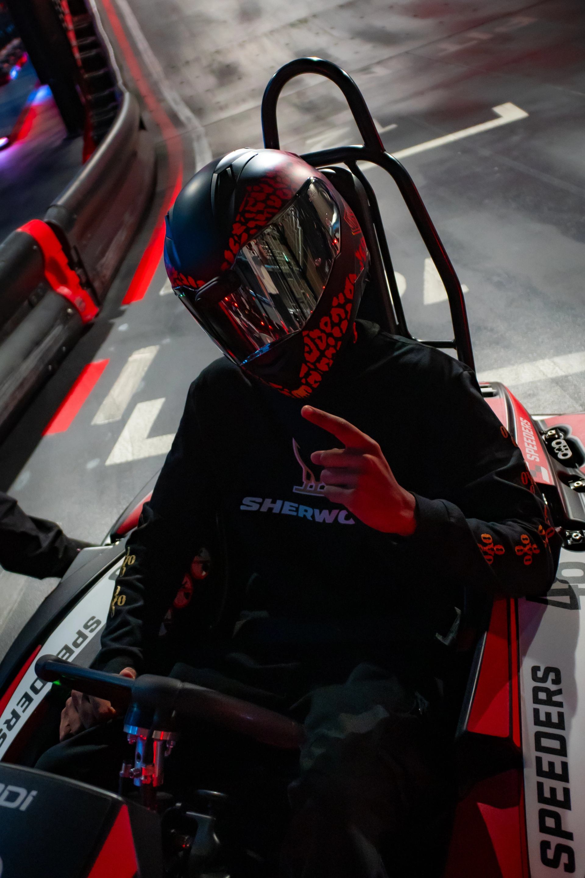 Person in helmet seated in a go-kart at Speeders indoor track.