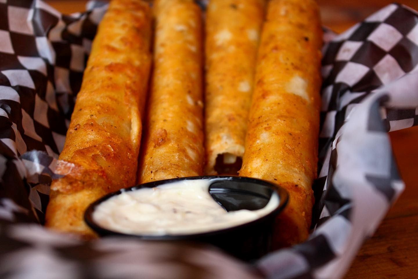 Basket of crispy rolled snacks with dipping sauce.