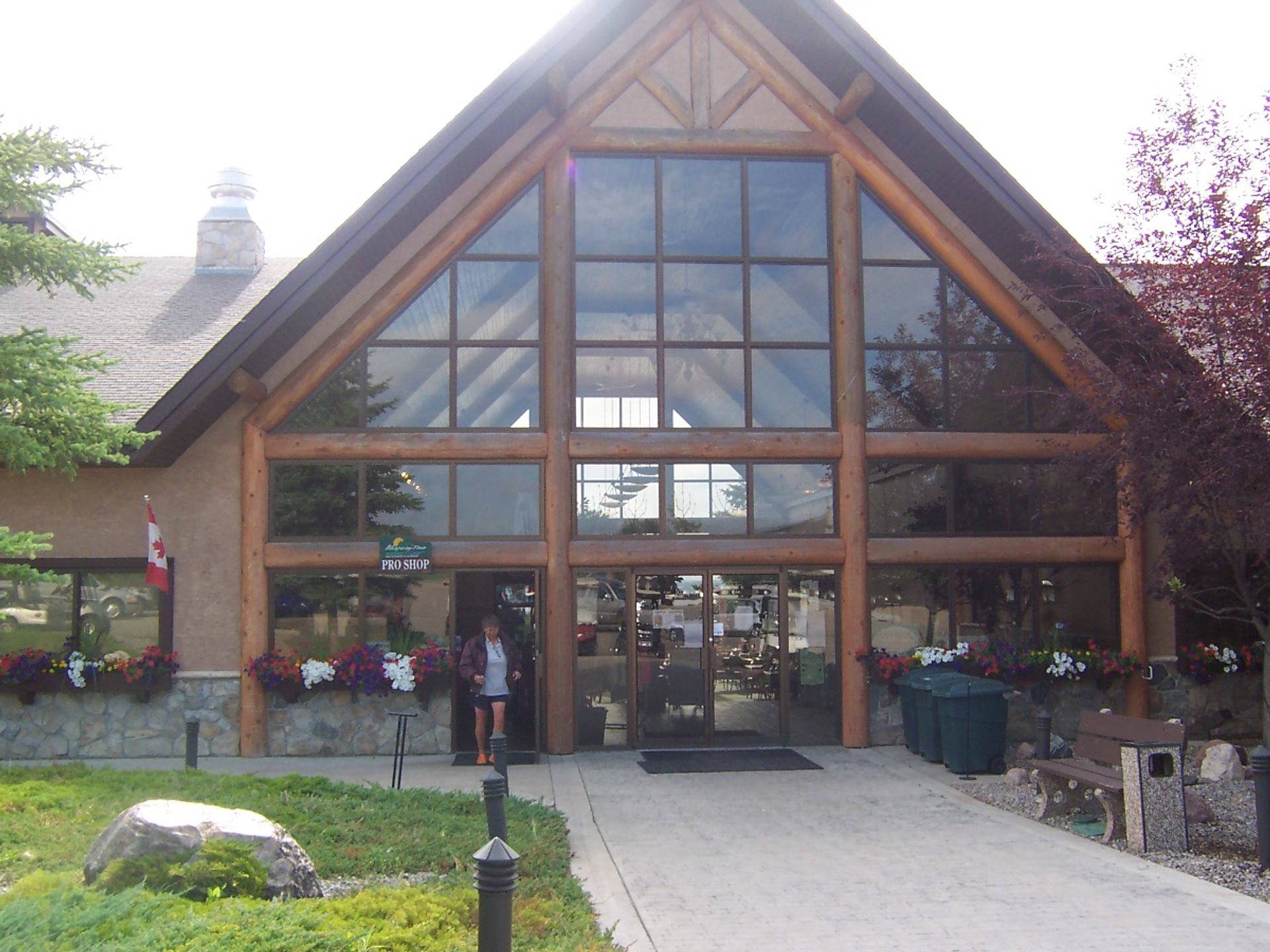 Lodge-style pro shop entrance with large windows, flower boxes and Canadian flag.