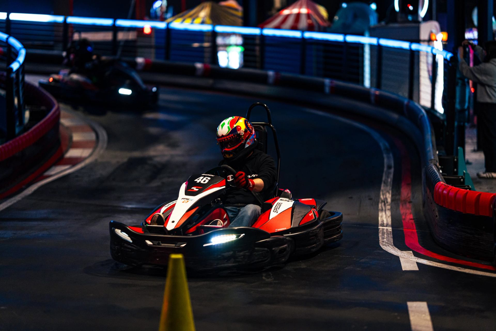 Go-kart speeding around an indoor track with bright lights and colorful barriers at Speeders.