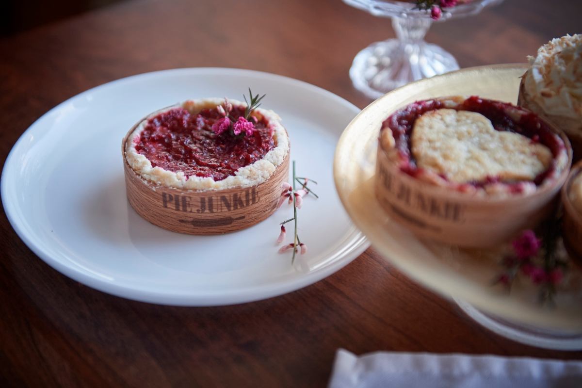 A "Pie Junkie" fruit tart on a white plate, with a heart-shaped pie in the background.