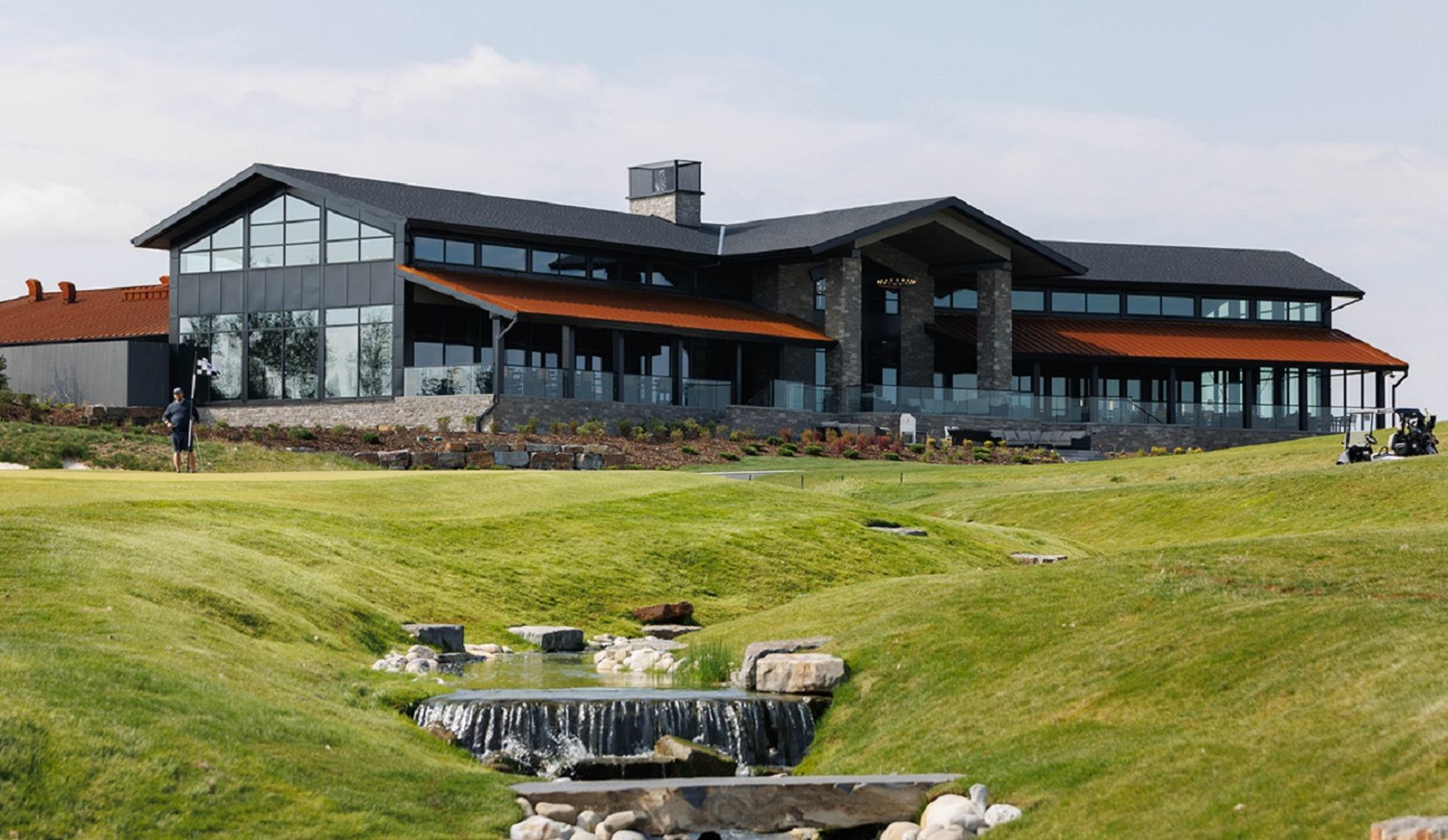 Contemporary clubhouse at Mickelson National Golf Club with scenic waterfall view.
