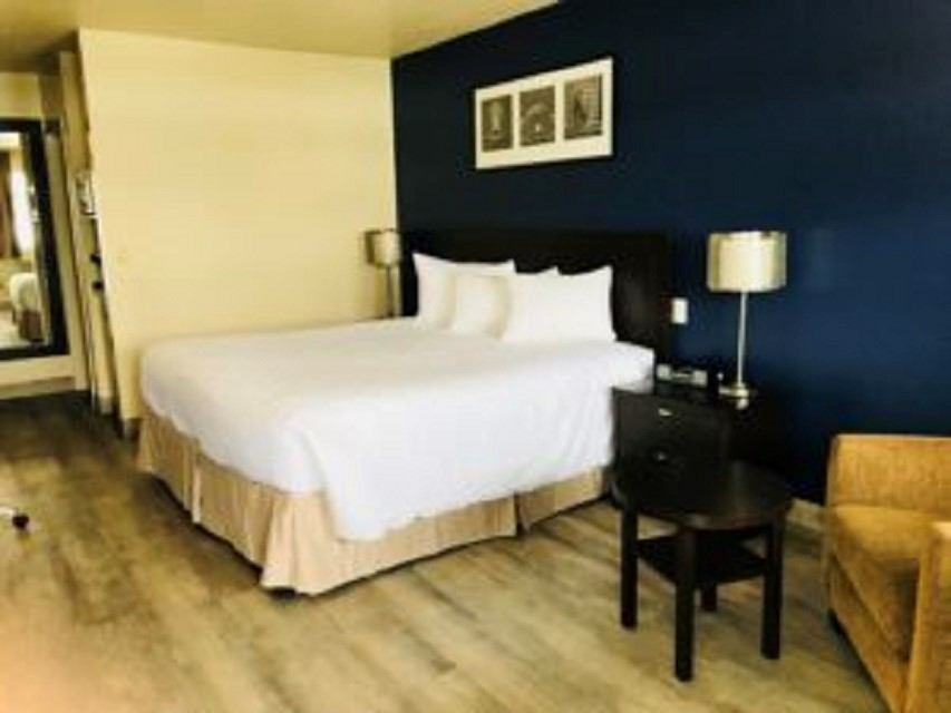 Hotel room with white bed linens, blue accent wall, lamps, and framed art.