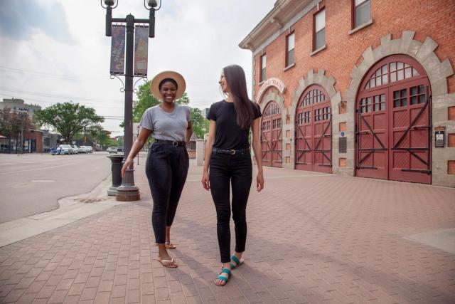 Two young women walking and talking in front of the Walterdale Theatre in Edmonton, Alberta.