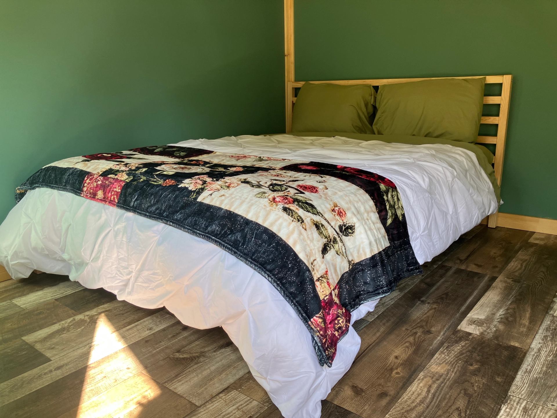 Bed with colorful quilt and green walls in a cozy wooden cabin