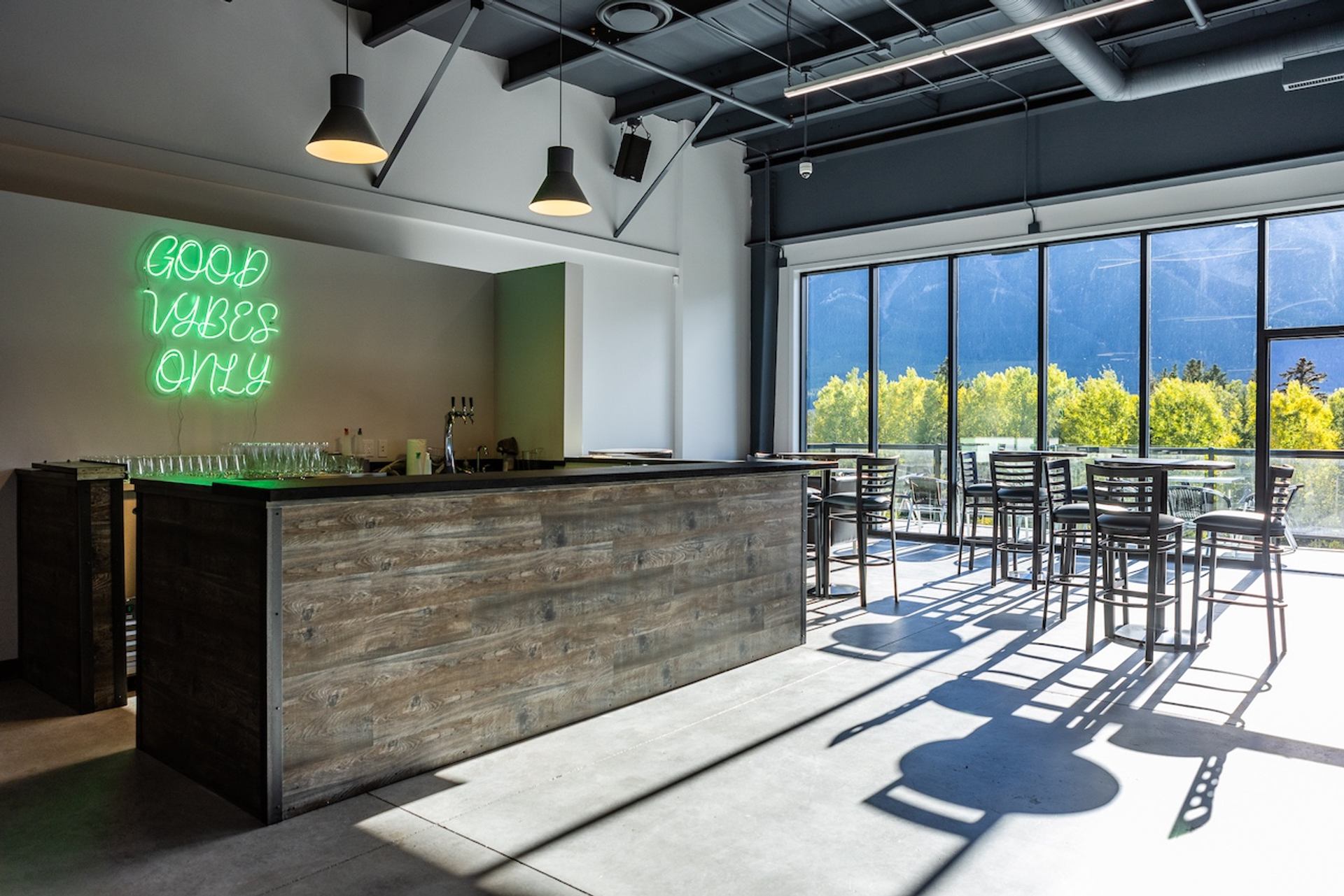 Modern bar with neon sign and large windows overlooking trees and mountains