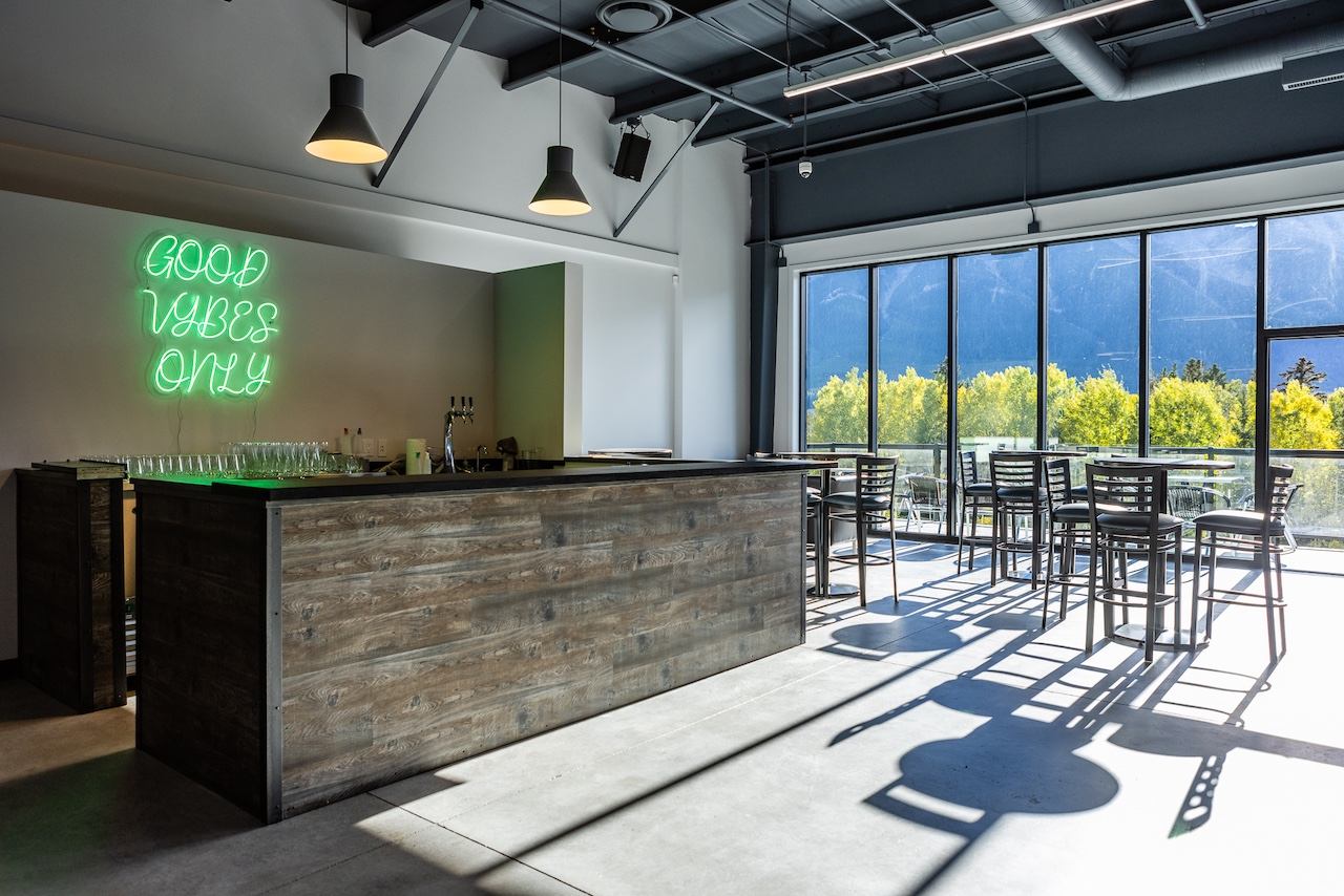 Modern bar with neon sign and large windows overlooking trees and mountains