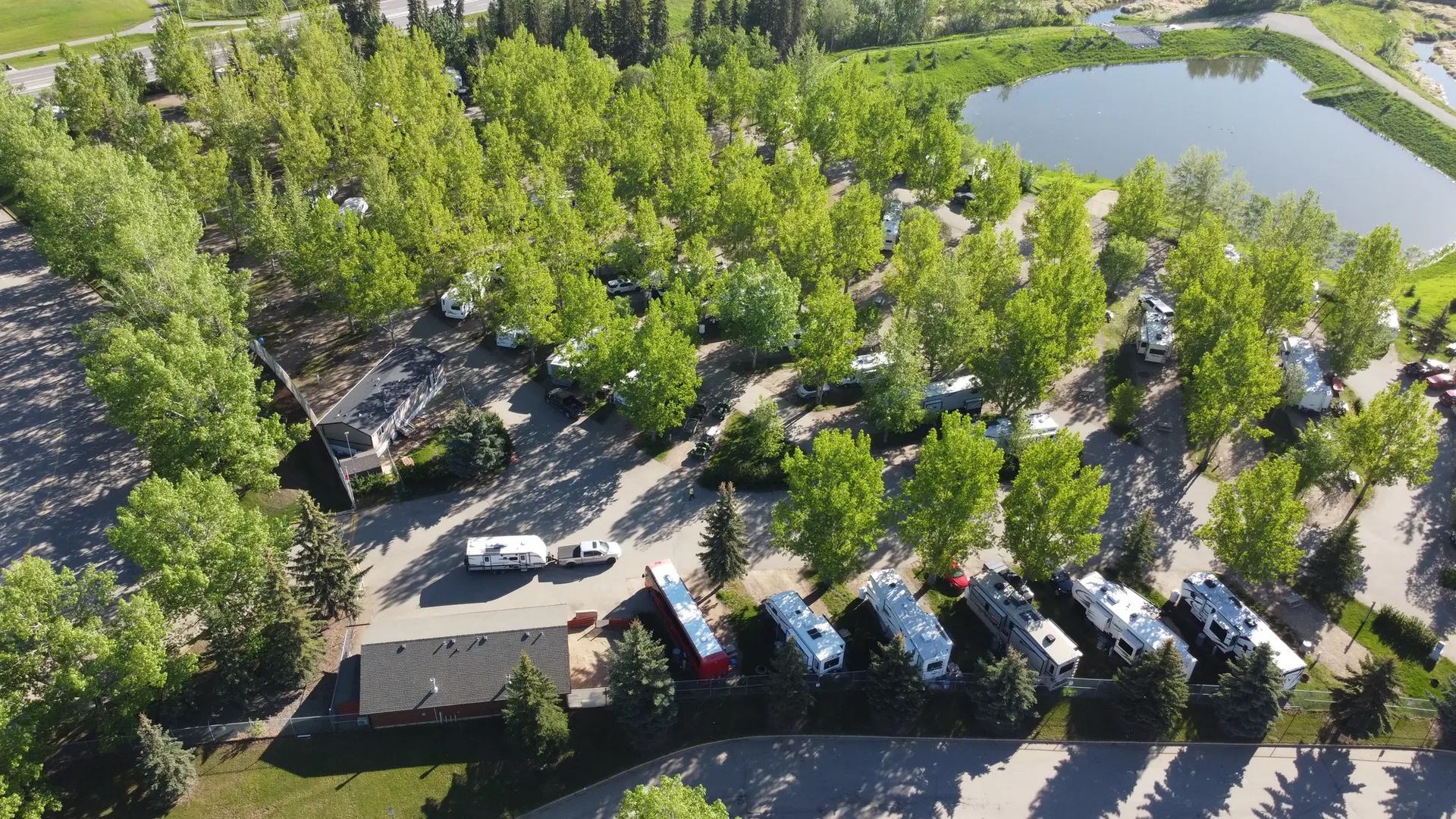 Aerial view of RV park with campers nestled among tall trees.