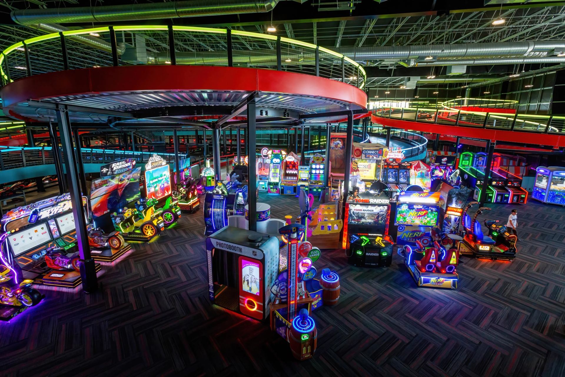 Bright arcade area at Speeders featuring colorful game machines and neon lights under a modern track.