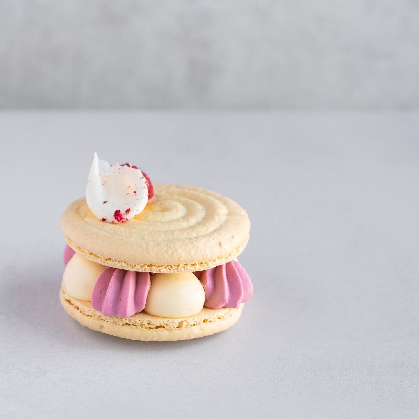 Danish pastry with purple and white icing and a cream cone topping on a plate.