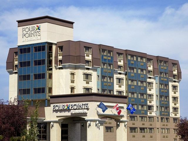Exterior of Four Points by Sheraton with modern design and flags near the entrance.
