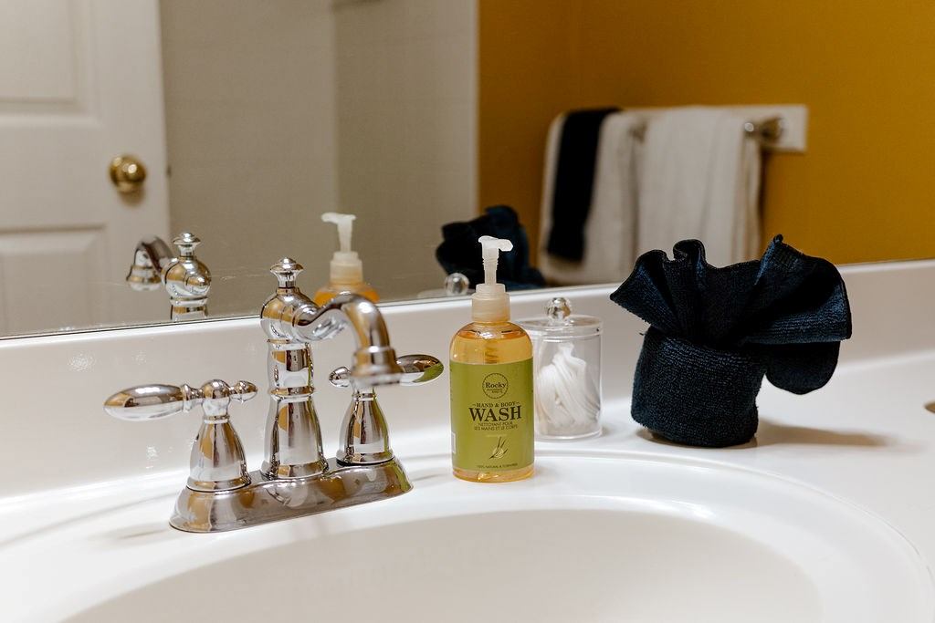 Bathroom sink with chrome taps, soap pump, and folded dark towels on counter.