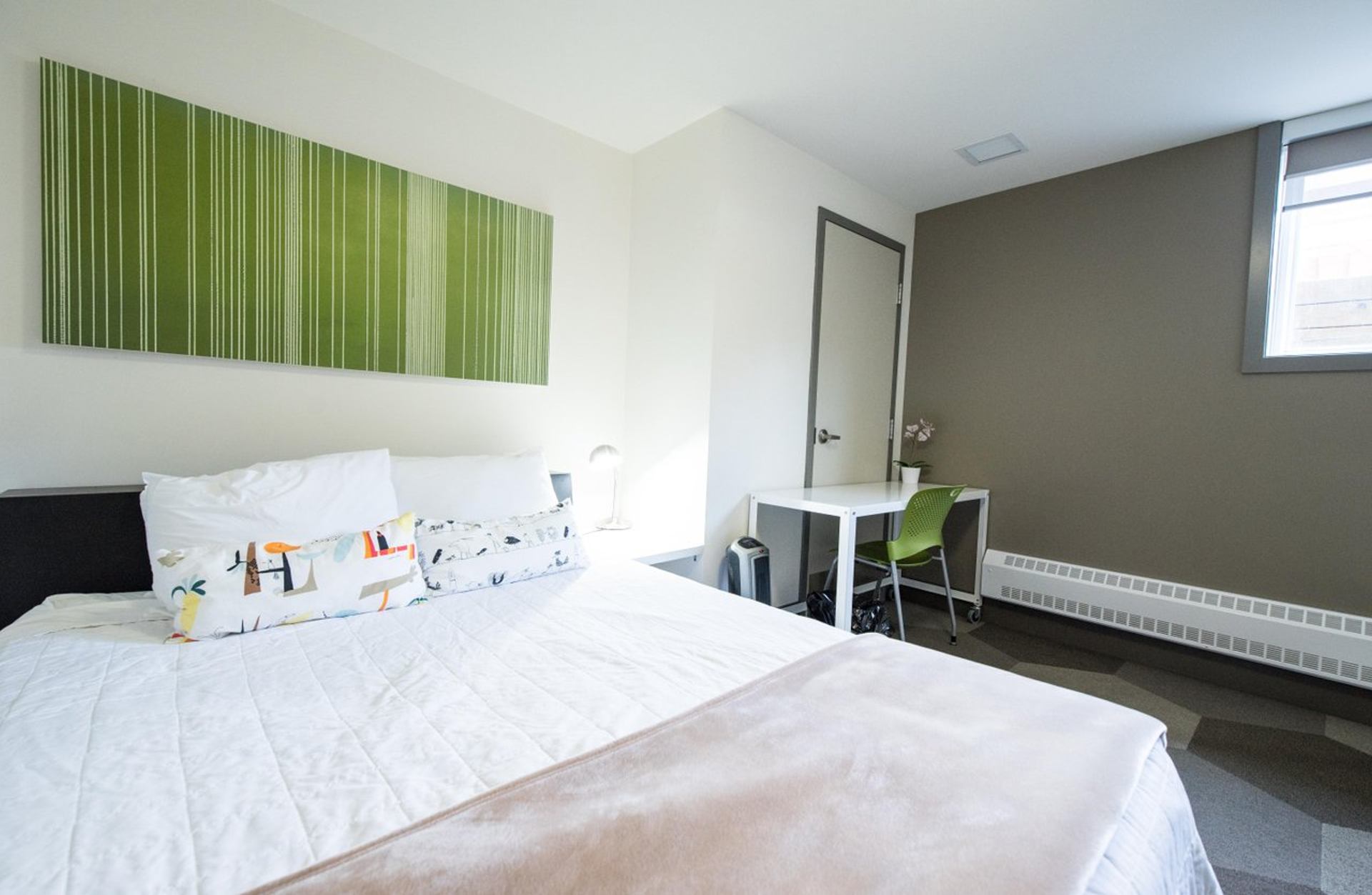 Cozy hotel room with bed, desk, and green decor.