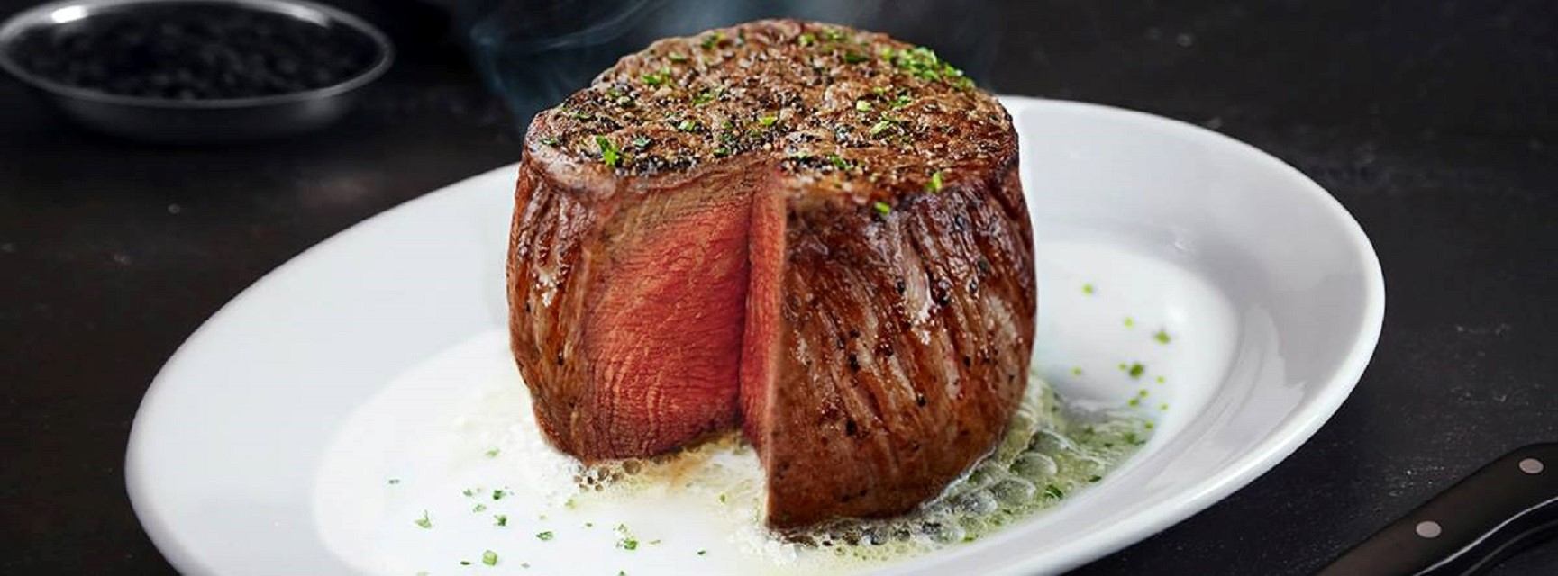 A filet mignon with its centre cut to show medium-rare doneness.