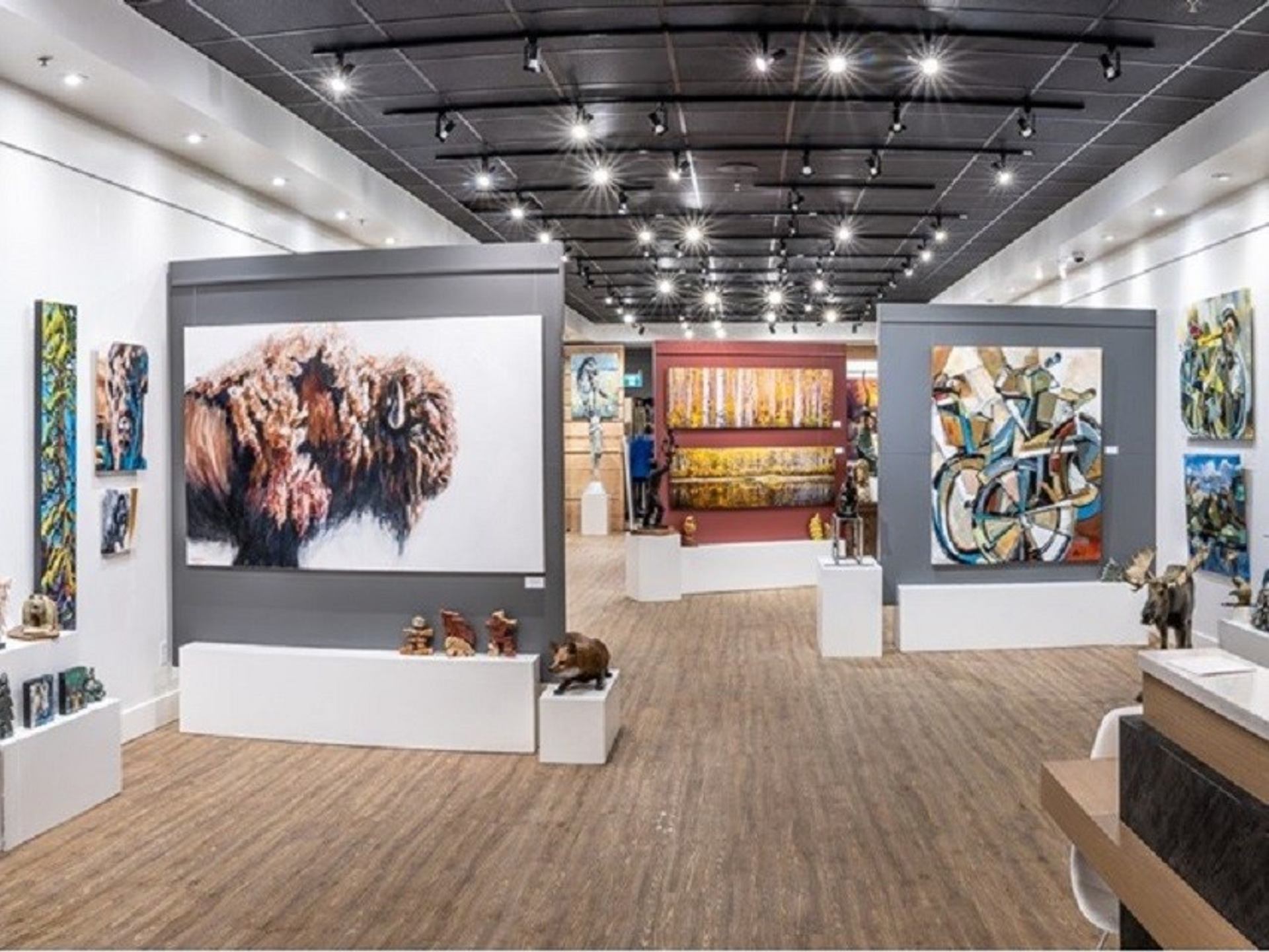 Gallery interior with large wildlife and abstract paintings displayed on bright, modern walls.