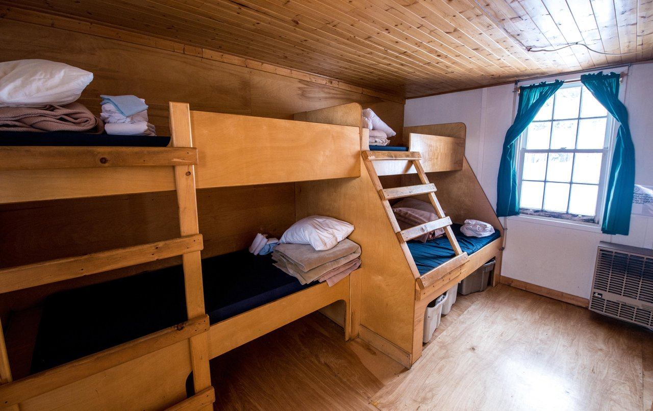 Cabin-style room with bunk beds, mattresses, and a window with natural light.