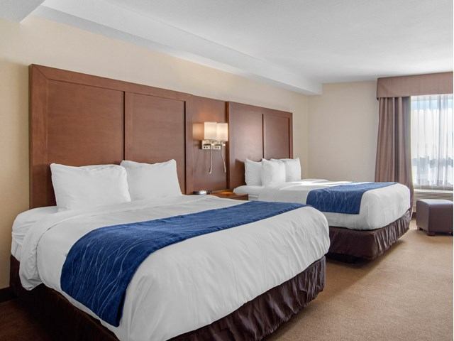 Hotel room with two beds, bedside lamps, and a window with curtains.