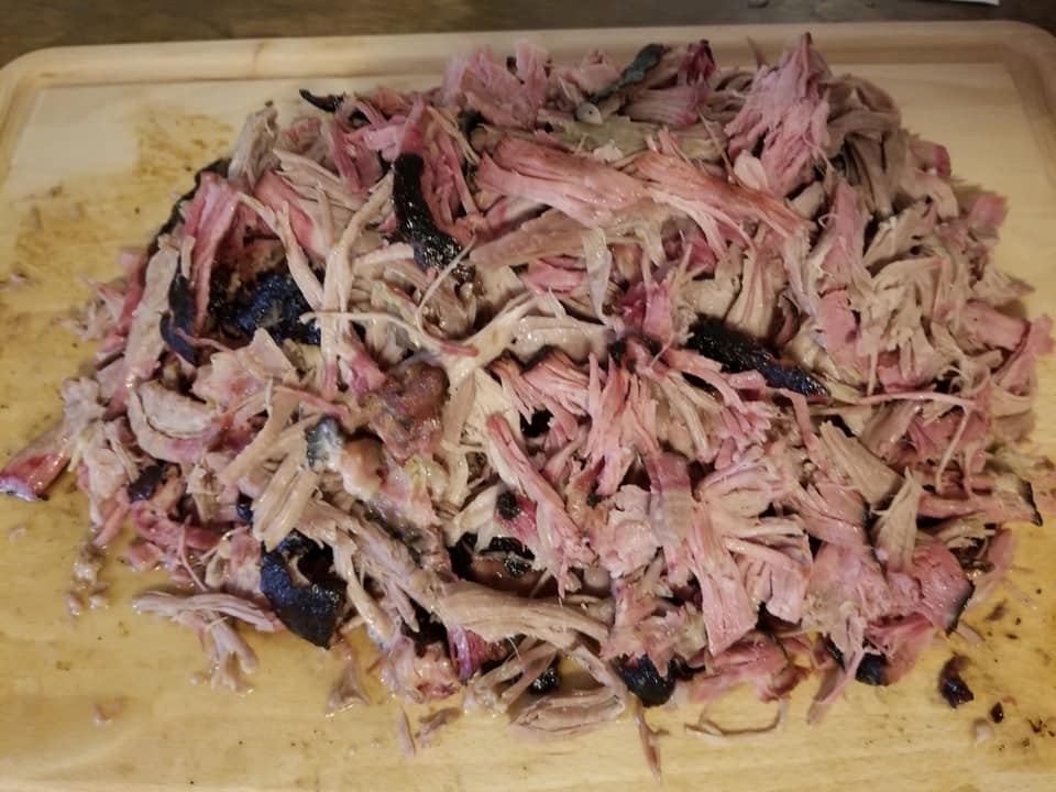 Pile of shredded barbecue meat on a wooden cutting board.