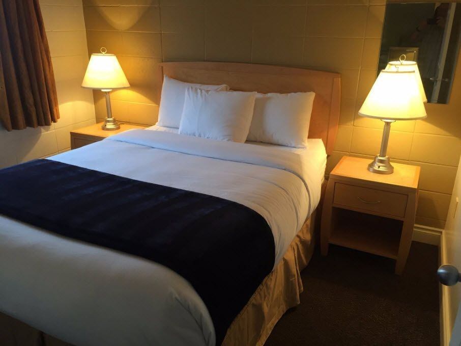 Cozy hotel room with queen bed, two bedside tables, and warm lighting.