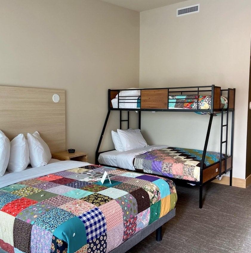 Double bed and bunk bed with patchwork quilts in a warm room at Métis Crossing Lodge.
